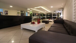 Una sala moderna con una mesa de centro blanca, sofás oscuros y un árbol de Navidad.