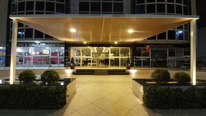 Un edificio moderno con vestíbulo cubierto, ventanas de vidrio y suelo de baldosas.