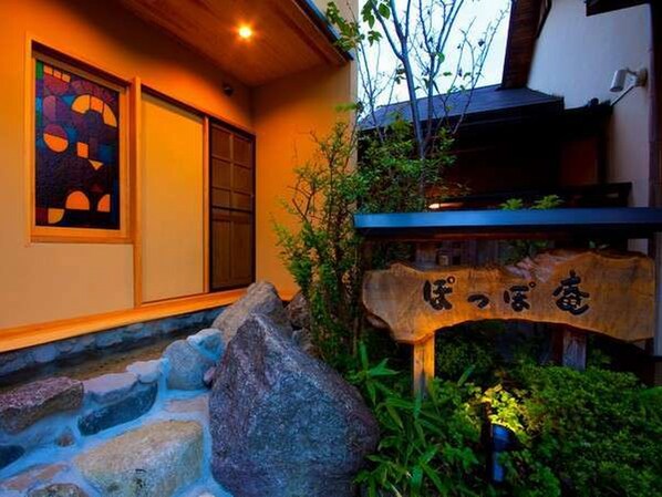 Un edificio japonés tradicional con un letrero de madera, una escalera de piedra y vista al cielo.