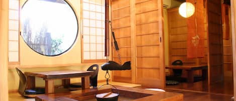 Una stanza tradizionale giapponese con pavimenti in tatami, una finestra rotonda e porte scorrevoli.