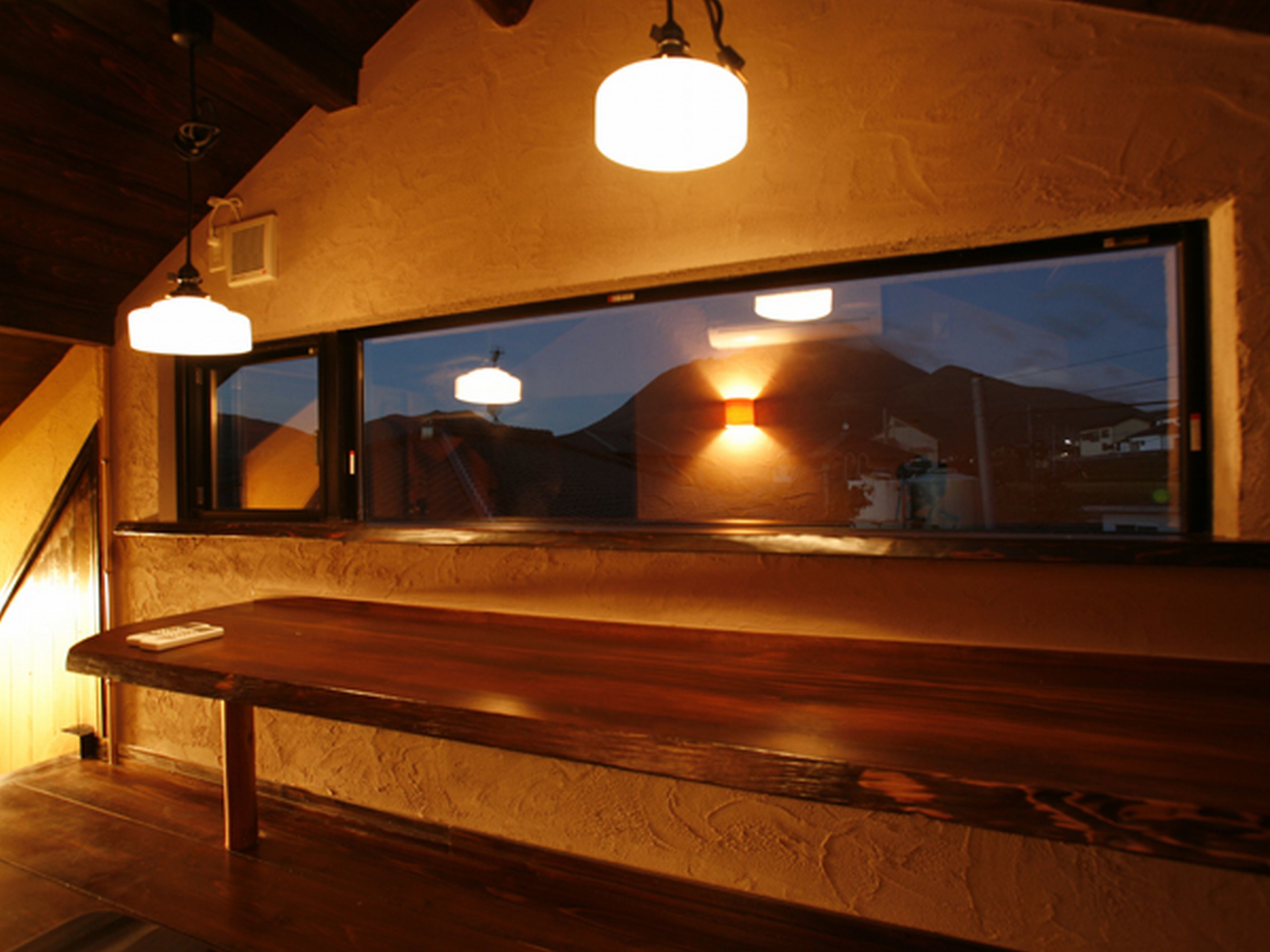 A bar area with wooden counter and hanging pendant lights.