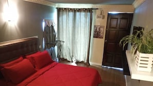 A bedroom with a bed, curtains, a door, and a plant. - Tamara Resort (Tioman Island)