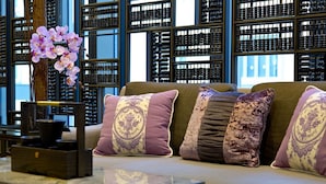 A modern interior with a sofa, patterned cushions, a vase with flowers, and a wine rack in the background. - Wanchai 88 Hotel (Hong Kong)
