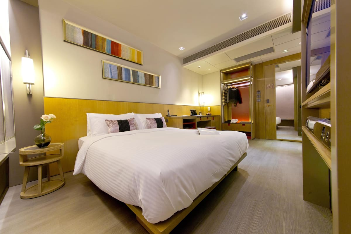 A hotel room with a large bed, bedside tables, a mirror, and a wardrobe.