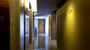 A modern hotel hallway with a reflective floor, a number '30' sign on the wall, and a door at the end. - Wanchai 88 Hotel (Hong Kong)