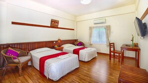 A hotel room with two beds, a wooden floor, a television, a small table, and a window with curtains. - Sakura Inn (Nyaung-U)