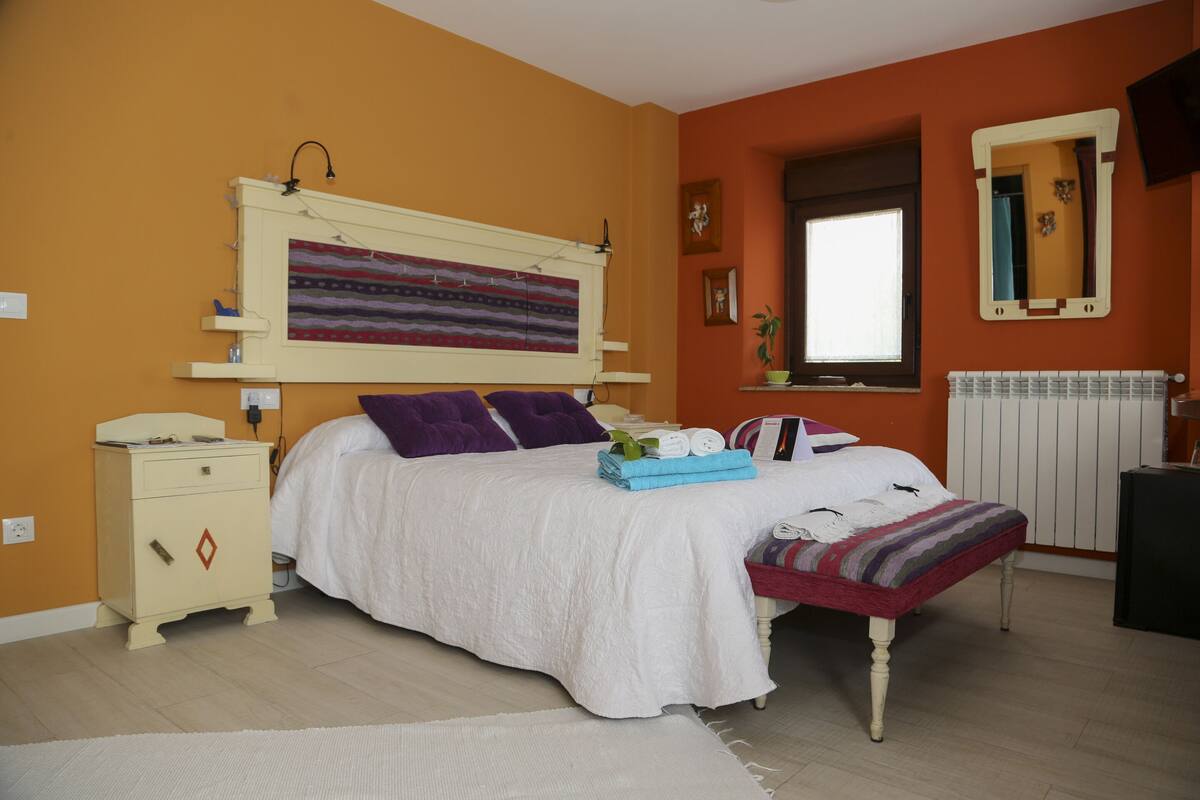 Une chambre à coucher comprenant un lit, une table de chevet, une commode, une fenêtre et un miroir fixé au mur.