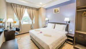 A hotel room with a large bed, bedside lamps, a desk with a chair, a wardrobe, and a window with curtains. - InHotel Inanam Kota Kinabalu (Kota Kinabalu)