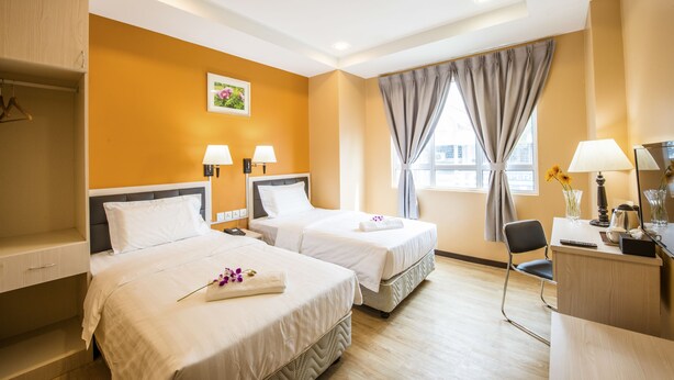 A hotel room with two beds, a desk, a chair, a window with curtains, and a wall-mounted picture. - InHotel Inanam Kota Kinabalu (Kota Kinabalu)