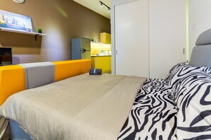 A hotel room with a bed, a sofa, a TV, a kitchen area, and a wardrobe. - Luzzeri Suite Empire Damansara (Petaling Jaya)