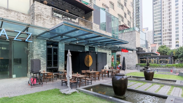 An outdoor dining area with tables and chairs, a covered seating area, and a small water feature. - Luzzeri Suite Empire Damansara (Petaling Jaya)