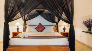 A bed with a canopy, two bedside lamps, and a decorative pillow. - Villa Bali Caviar (Seminyak)