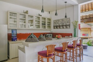 Cozinha moderna com ilha central, banquetas e dispensador de água.