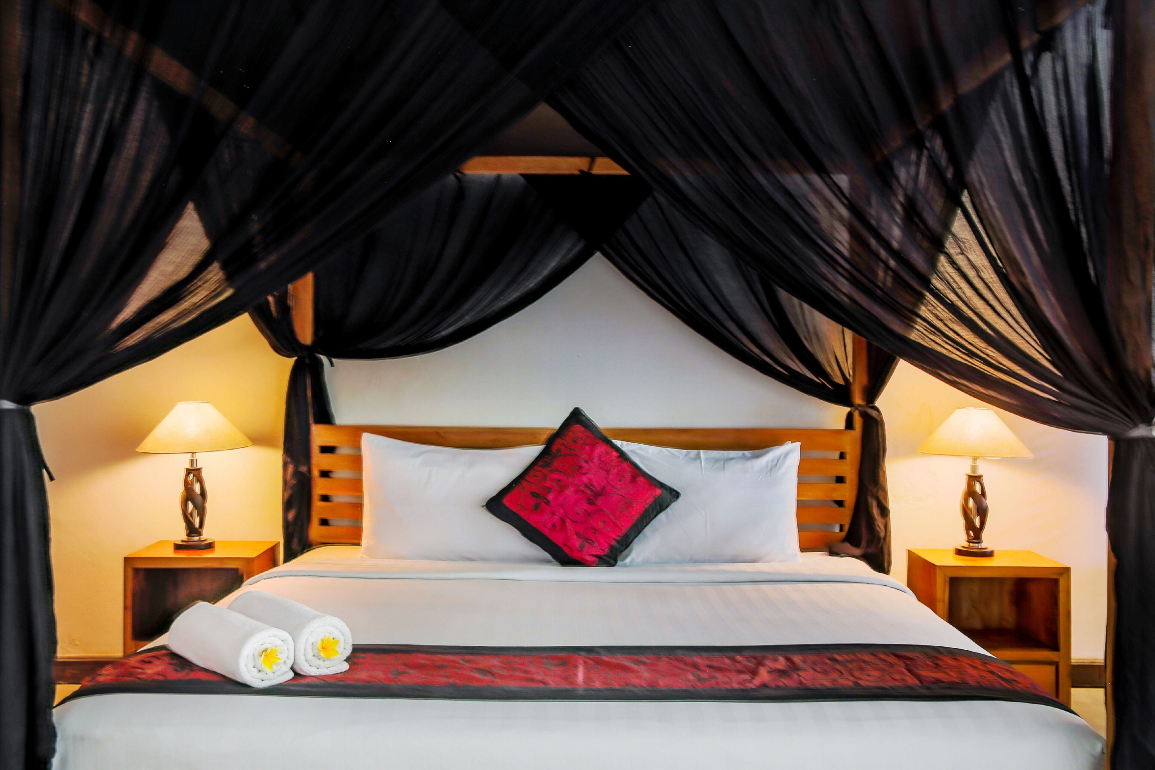 A hotel room with a bed, two bedside tables, and a canopy bedspread.