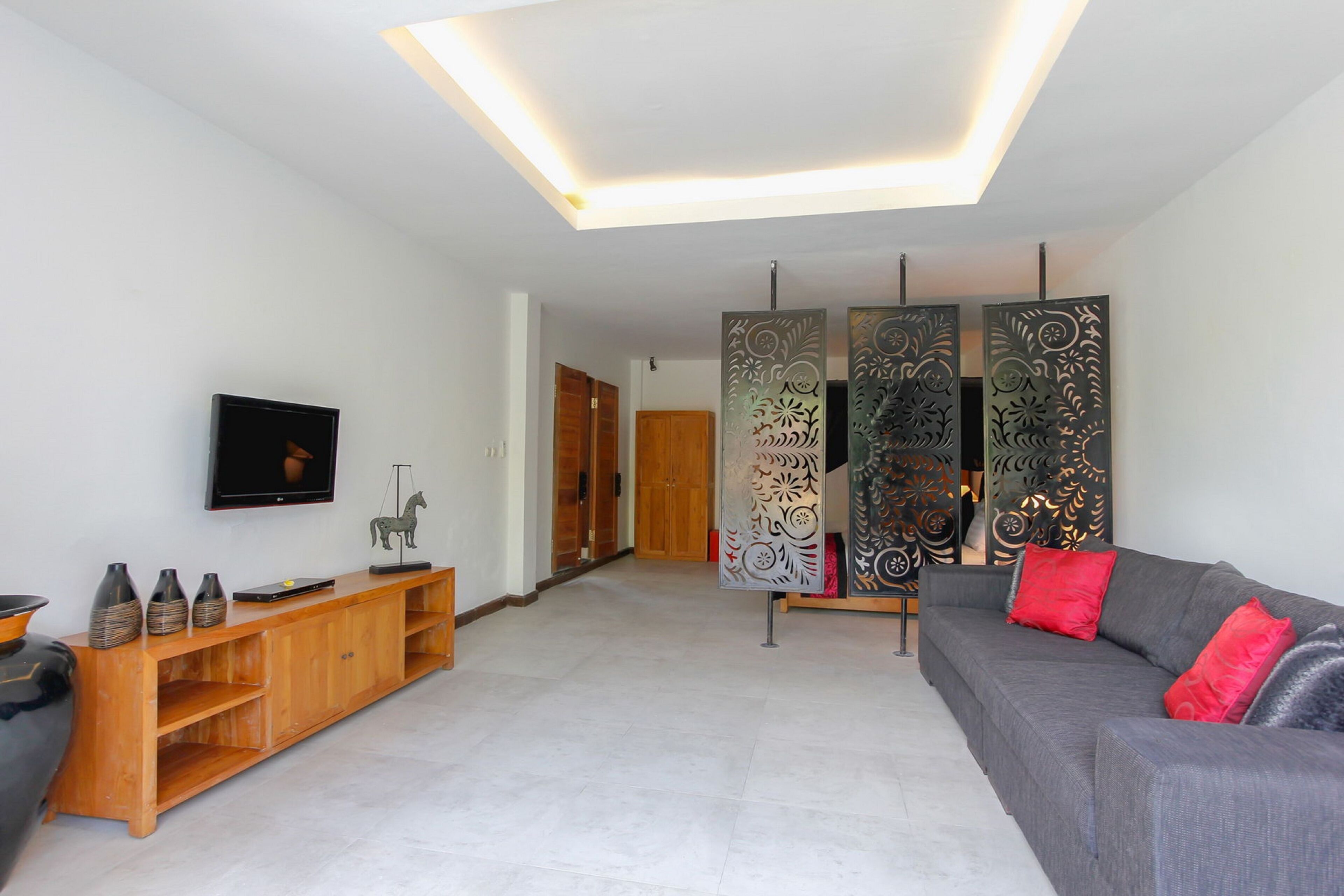 Una sala de estar moderna con un sofá gris, mueble de entretenimiento de madera, paneles decorativos y un televisor de pantalla plana.