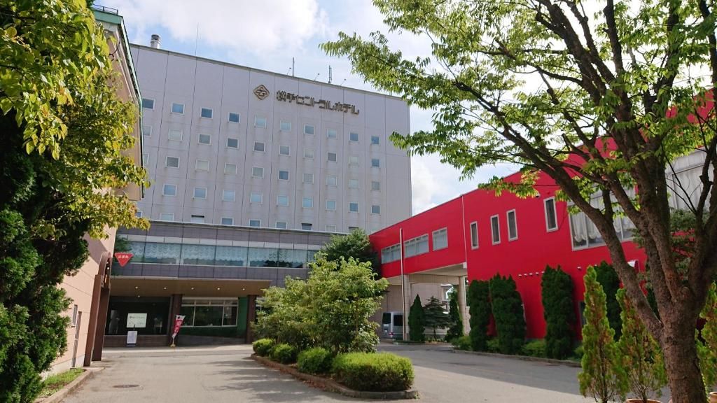 Un edificio con fachada moderna, un edificio rojo contiguo a él y un jardín bien cuidado.