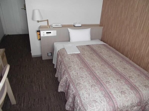 A hotel room with a bed, a bedside table with a lamp, a phone, and a control panel. - Yokote Central Hotel (Yokote)