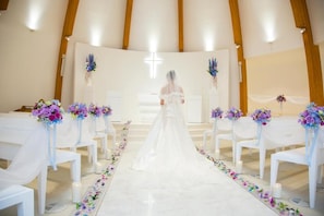 A church interior with white chairs arranged in rows, a central aisle, and floral decorations. - Yokote Central Hotel (Yokote)