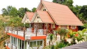 Una casa de dos pisos con techo rojo y un balcón.