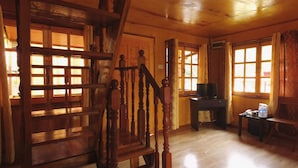 A wooden interior with a staircase, a television on a desk, and large windows. - Borneo Tree House (Kota Kinabalu)