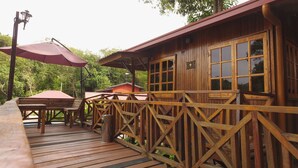 A wooden cabin with a deck, a red umbrella, and a number '9' sign. - Borneo Tree House (Kota Kinabalu)