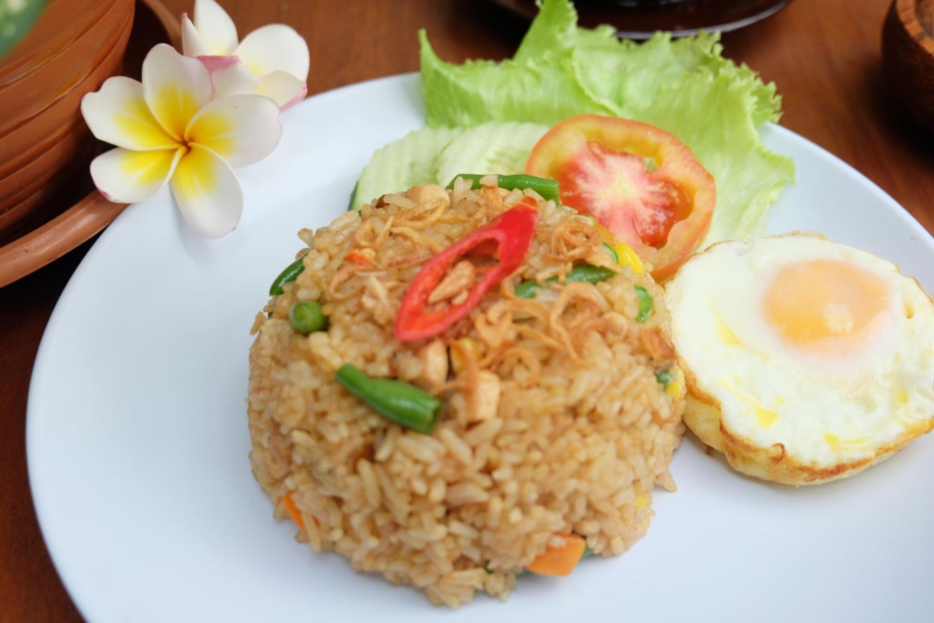 A plate of fried rice with vegetables and a fried egg.