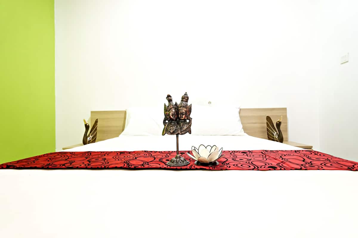 Una cama con una colcha de cuadros roja y negra, dos cabeceros de madera y un objeto decorativo sobre la cama.