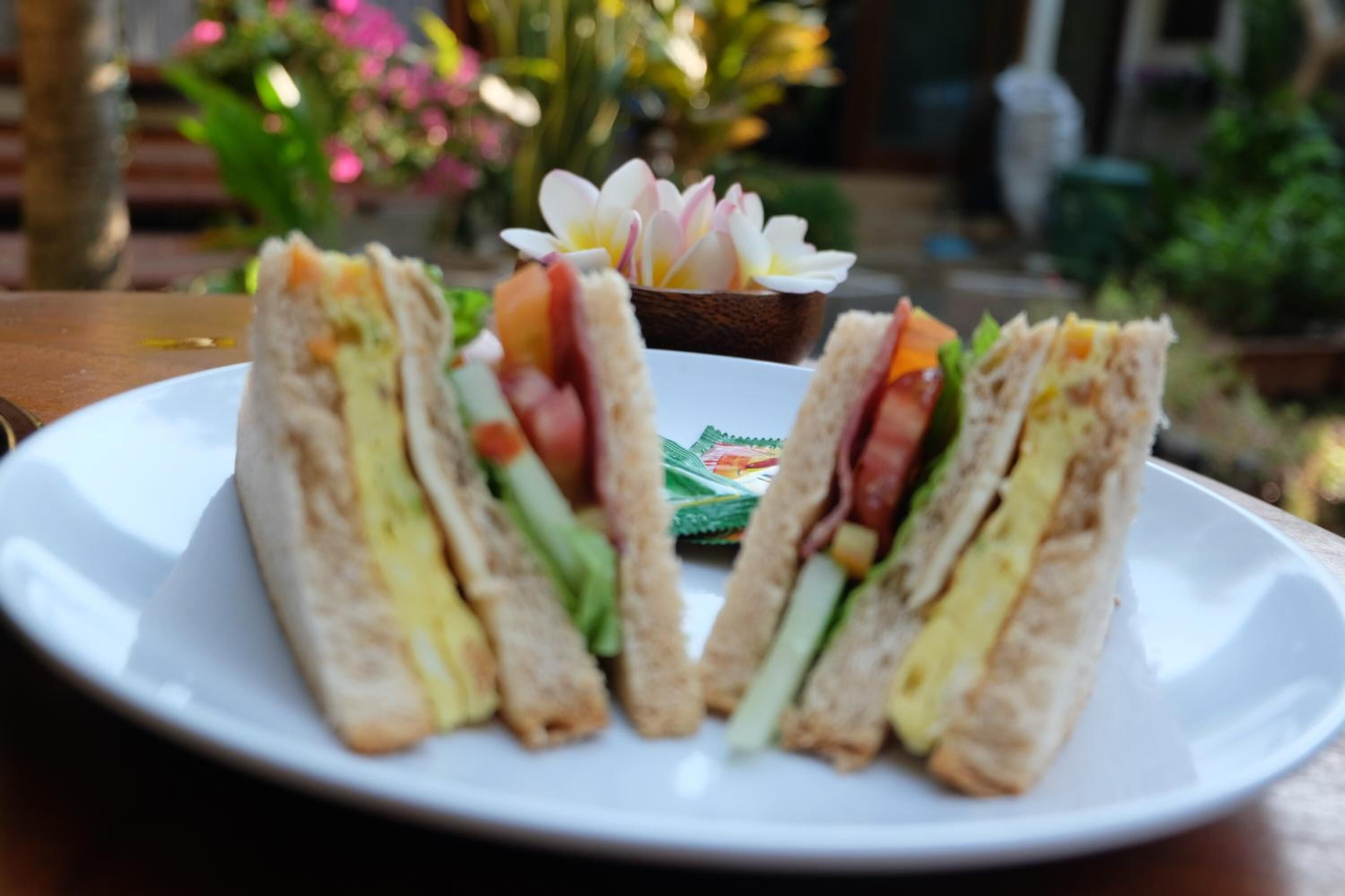 A plate with a sandwich and a small bowl of flowers.