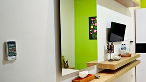 A modern bathroom with a large mirror, a mounted television, and a wooden vanity. - D'Pande (Kuta)