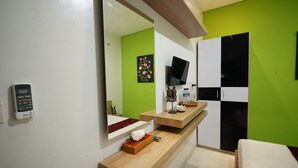 A modern bathroom with a green wall, a mirror, a sink, a toilet, and a shower area. - D'Pande (Kuta)