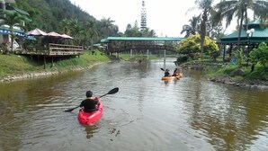 Un río con kayaks, un muelle de madera y un puente.