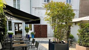 Ein Patio im Freien mit Steinboden, Sitzgelegenheiten und Kübelpflanzen.