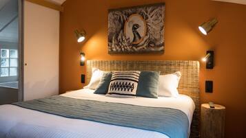 A neatly made bed with a blue and white striped bedspread, two pillows with geometric patterns, and a wall-mounted artwork above.