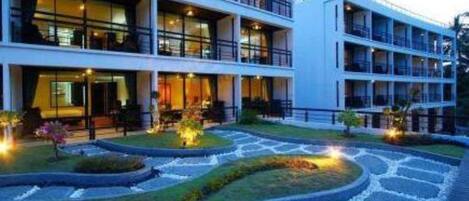 A modern hotel with multiple floors, a landscaped garden, and a well-lit entrance.
