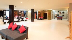 A spacious lobby with a reception desk, seating area with red cushions, and a pool table. - The Kris Resort Condotel at Bagtao Beach (Choeng Thale)