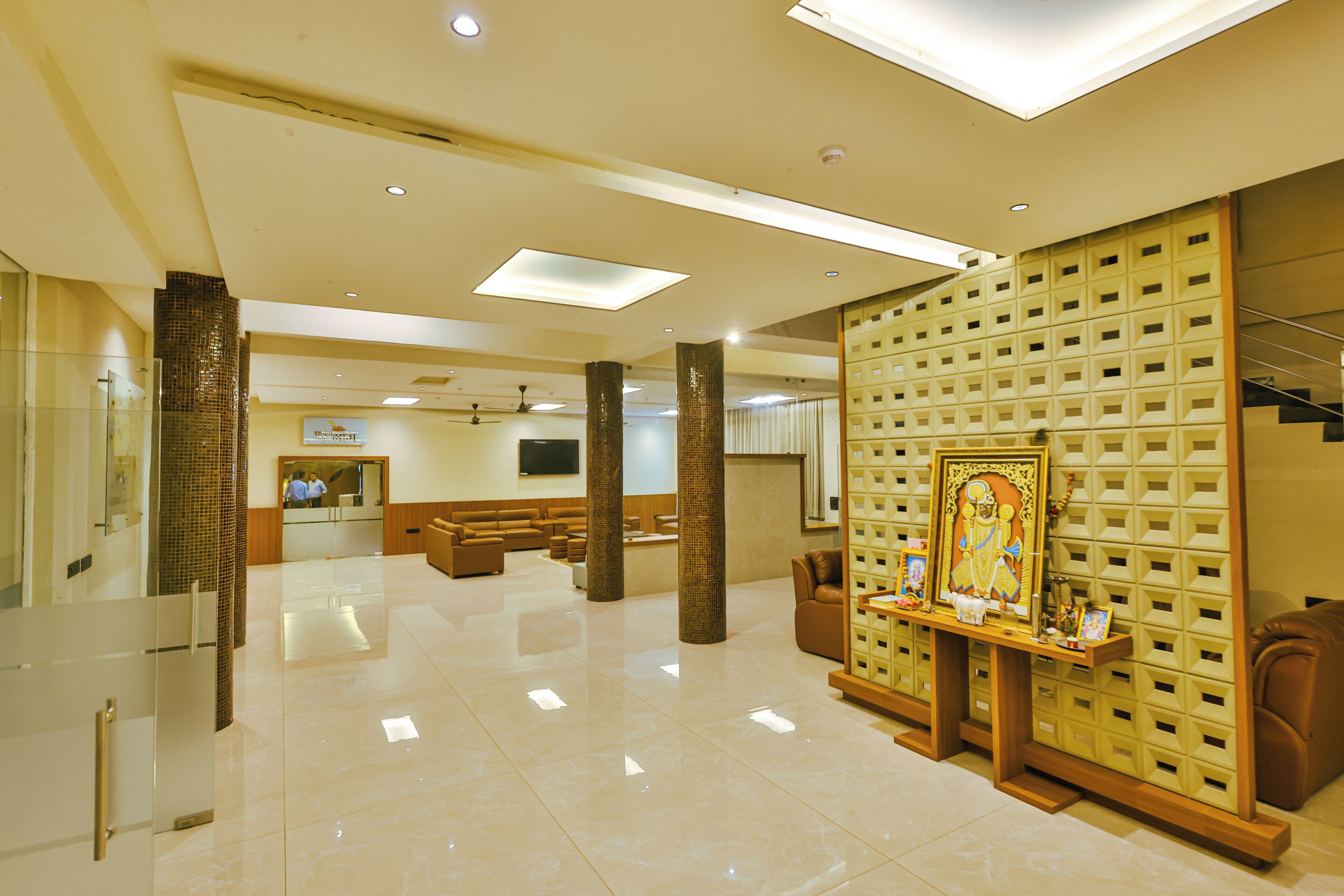 Um hall amplo com balcão de recepção, área de estar e parede decorativa com obra de arte emoldurada.