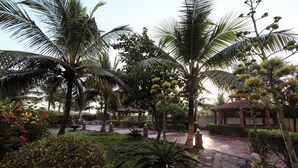 A garden with palm trees, a gazebo, and a paved walkway. - Goverdhan Greens Resort Dwarka (Dwarka)