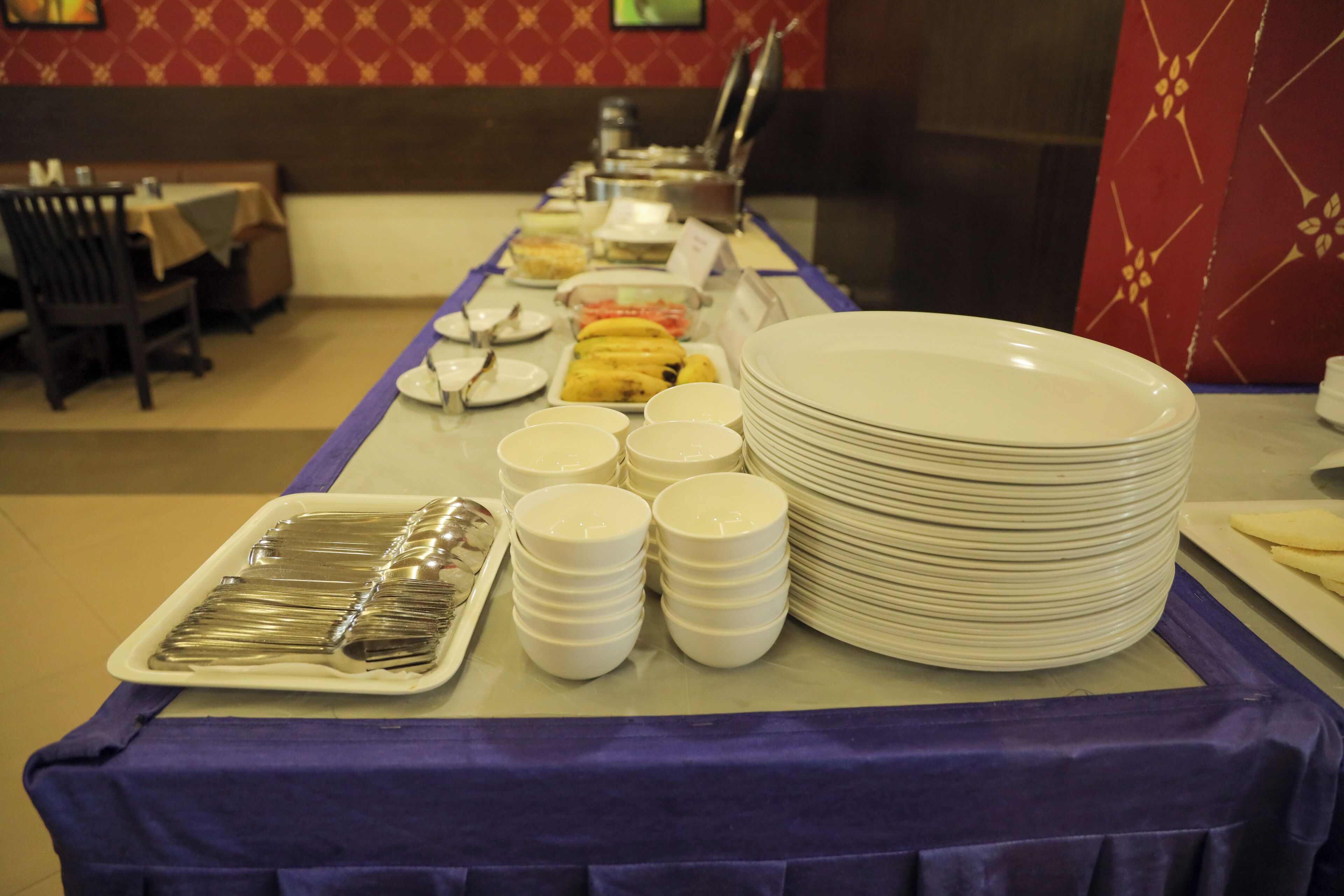 A buffet setup with plates, bowls, and utensils.