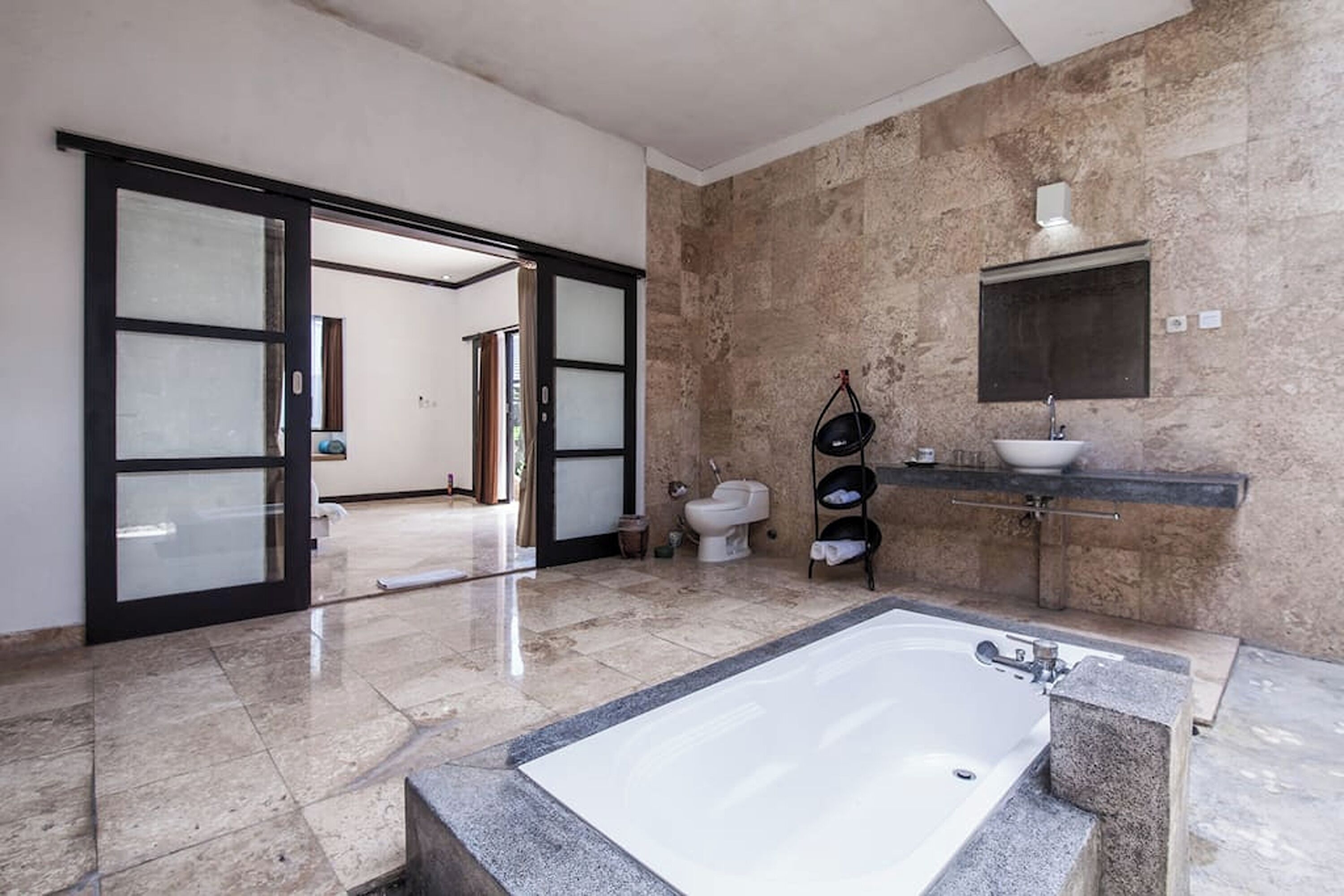 Un baño amplio con una bañera grande, un inodoro y un lavamanos.