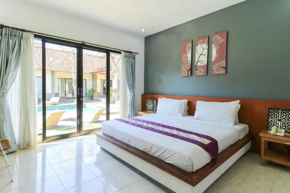 A hotel room with a large bed, a view of a pool, and a sliding glass door.