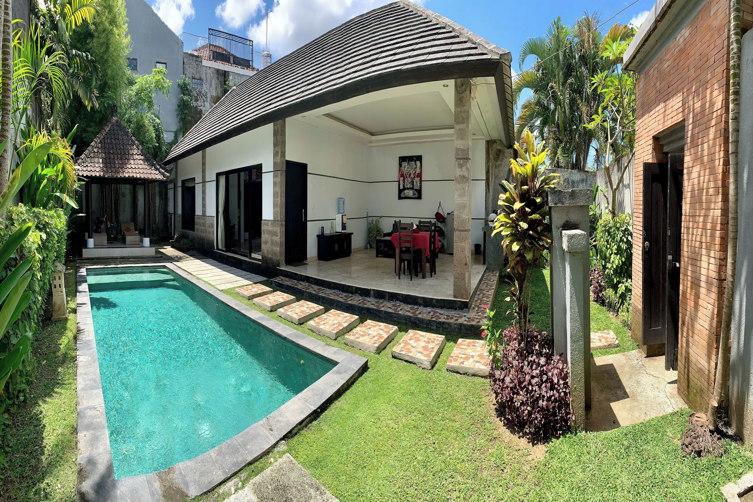 A poolside area with a covered patio, a swimming pool, and a small garden.