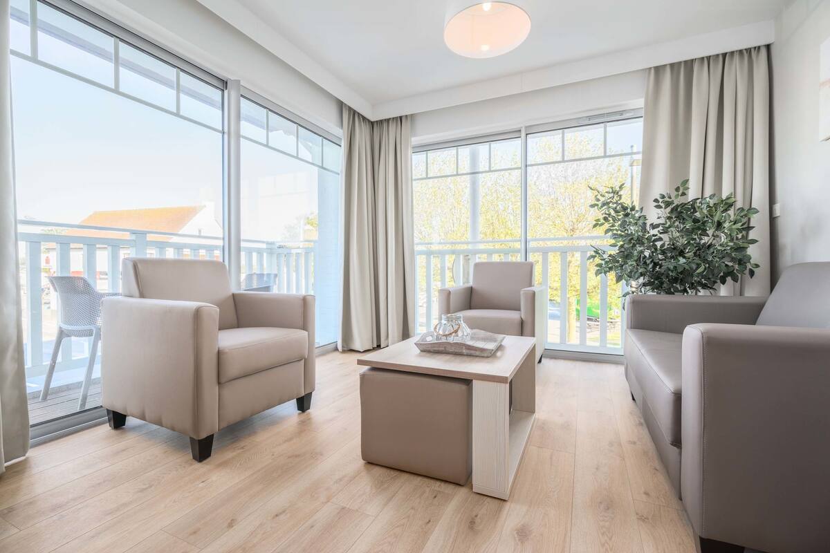 Una sala moderna con un sofá color beige, una mesa de centro y una planta en maceta.