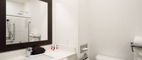 A modern bathroom with a white sink, a mirror, a towel rack, and a toilet.