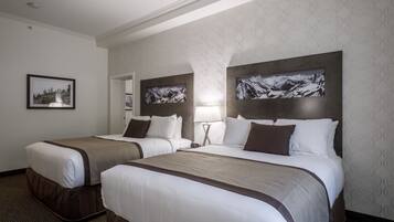 A hotel room with two beds, a framed picture on the wall, and a lamp.