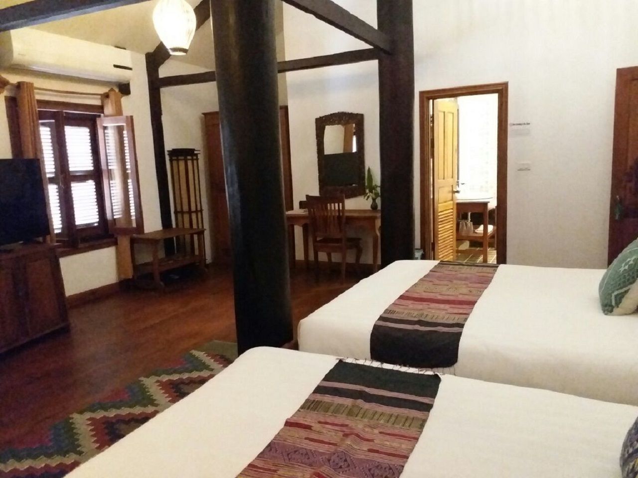 A room with two beds, wooden furniture, a desk, and a chair.