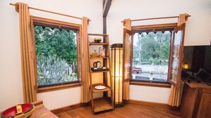 Una habitación con muebles de madera, una estantería con adornos, un farol y vista a una calle con árboles.