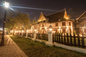 A traditional building with a curved roof, a fence with decorative posts, and a street lamp. - Royal Peacock Boutique Hotel (Luang Prabang)