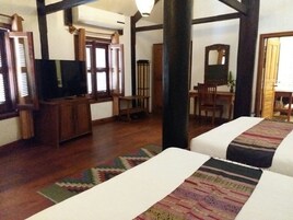 Une chambre comprenant un lit, un bureau, une chaise, un téléviseur et une fenêtre avec des stores.