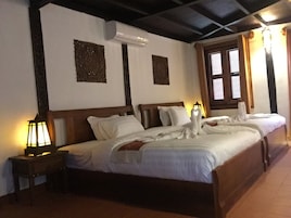 Una habitación de hotel con una cama grande, dos mesitas de noche, un aire acondicionado y una ventana con cortinas.