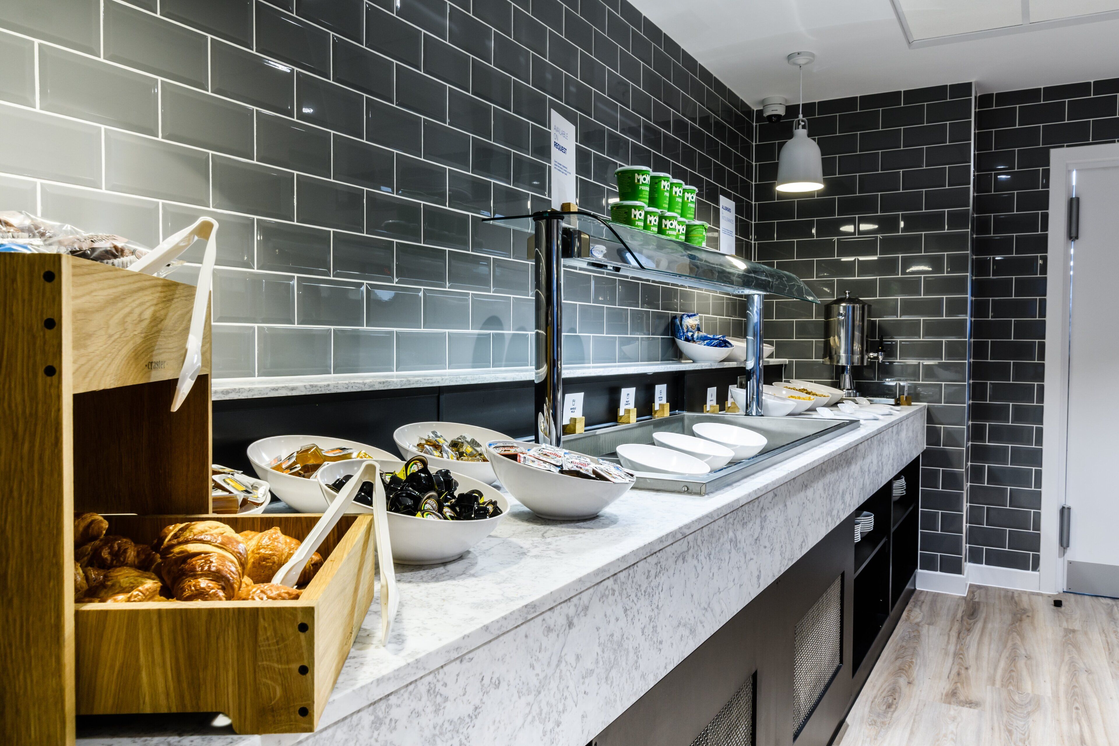 Una cocina moderna con encimera de mármol, salpicadero de azulejos negros y diversos alimentos y condimentos.